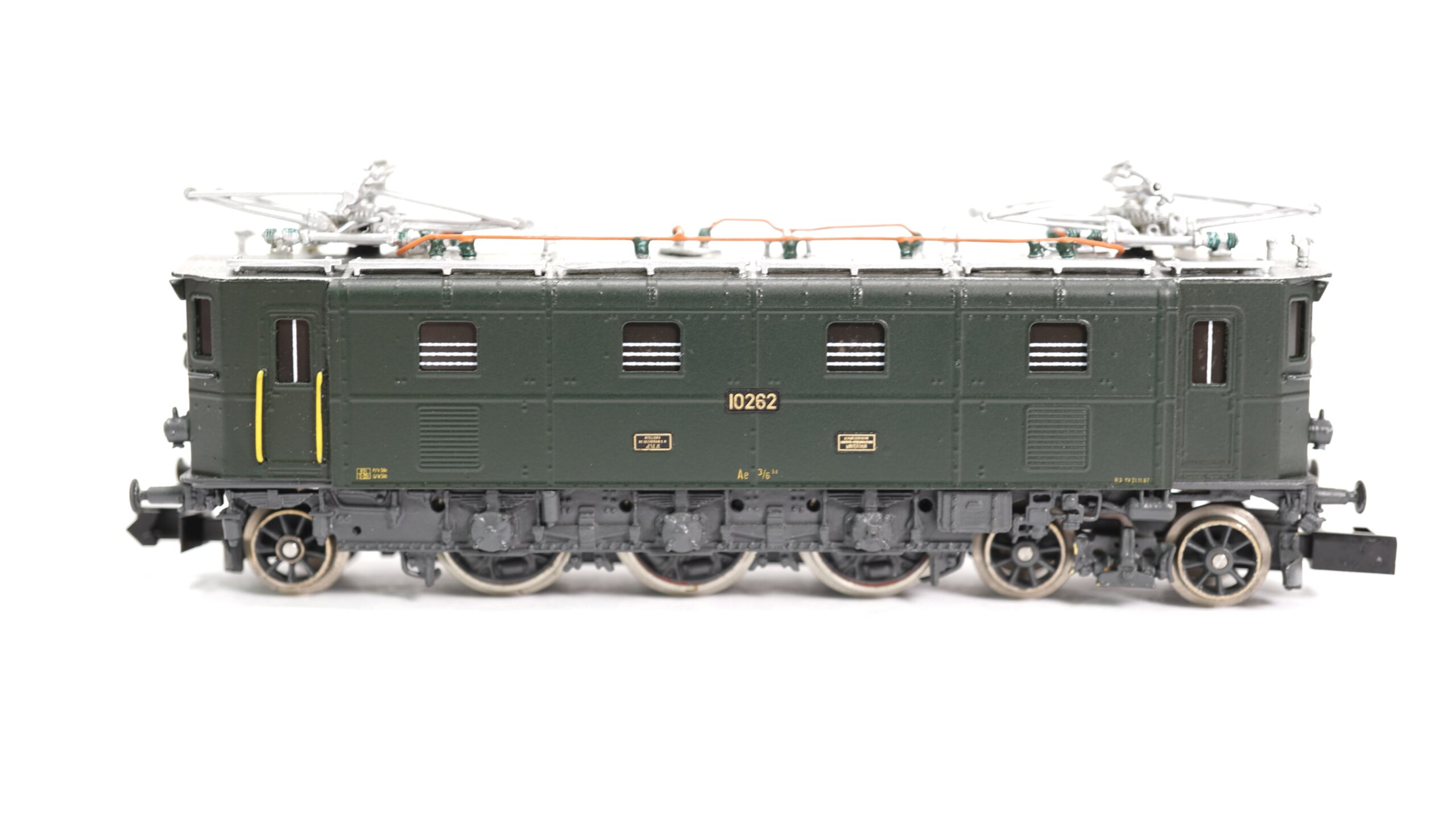Lemaco N-014/1 SBB Ae 3/6 III grün | 994 1 Lemaco N-014/1 – SBB Ae 3/6 III grün: Modell mit Geschichte und Eleganz Die Lemaco N-014/1 ist ein hochwertiges Modell der legendären Schweizer Elektrolokomotive Ae 3/6 III der SBB, ausgeführt in der klassischen grünen Farbgebung. Mit höchster Präzision gefertigt, vereint dieses Modell technische Raffinesse, historische Bedeutung und modellbauerische Exzellenz. Das Original der Ae 3/6 III wurde zwischen 1925 und 1930 von der Schweizerischen Lokomotiv- und Maschinenfabrik (SLM) und Brown, Boveri & Cie (BBC) entwickelt. Insgesamt wurden 26 Exemplare gebaut, die sich durch ihre Zuverlässigkeit und ihre innovative Technik auszeichneten. Die Ae 3/6 III war Teil eines umfassenden Modernisierungsprogramms der SBB in der Zwischenkriegszeit, das den vollständigen Übergang von Dampf- auf Elektrolokomotiven einleitete. Sie wurde speziell für den mittelschweren Reisezugdienst im Flachland konzipiert und war unter anderem auf der Strecke Zürich–Basel oder Zürich–St. Gallen im Einsatz. Charakteristisch für die Ae 3/6 III ist die asymmetrische Achsfolge (1’C1’) mit Blindwelle, die eine gute Laufruhe bei hohen Geschwindigkeiten ermöglichte. Die Lok erreichte eine Höchstgeschwindigkeit von 100 km/h – beachtlich für die damalige Zeit – und leistete rund 1.630 kW (2.200 PS). Dank ihrer Robustheit blieben viele Maschinen bis in die 1970er Jahre im aktiven Dienst. Das Lemaco-Modell in Spur N ist eine exklusive Kleinserie aus Messing-Handarbeit. Es überzeugt durch exakte Proportionen, feinste Gravuren, korrekt nachgebildete Dachausrüstung mit filigranen Stromabnehmern und ein originalgetreues Fahrgestell. Der typische grüne Anstrich mit korrekt ausgeführten Anschriften und Loknummer rundet das authentische Erscheinungsbild ab. Dieses Modell ist nicht nur für SBB-Fans ein Höhepunkt in der Sammlung, sondern auch ein eindrucksvolles Beispiel Schweizer Eisenbahngeschichte im Maßstab 1:160. Die Kombination aus technischer Finesse und eleganter Erscheinung macht die Lemaco Ae 3/6 III zu einem gesuchten Sammlerstück – insbesondere in dieser makellos ausgeführten Version.